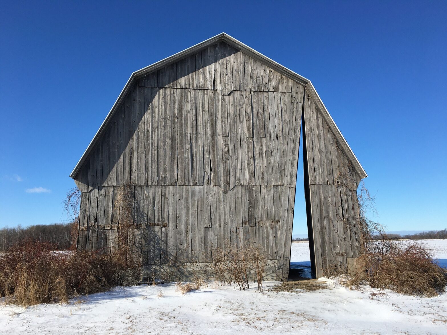 Old barn missing slats in a snowy field
